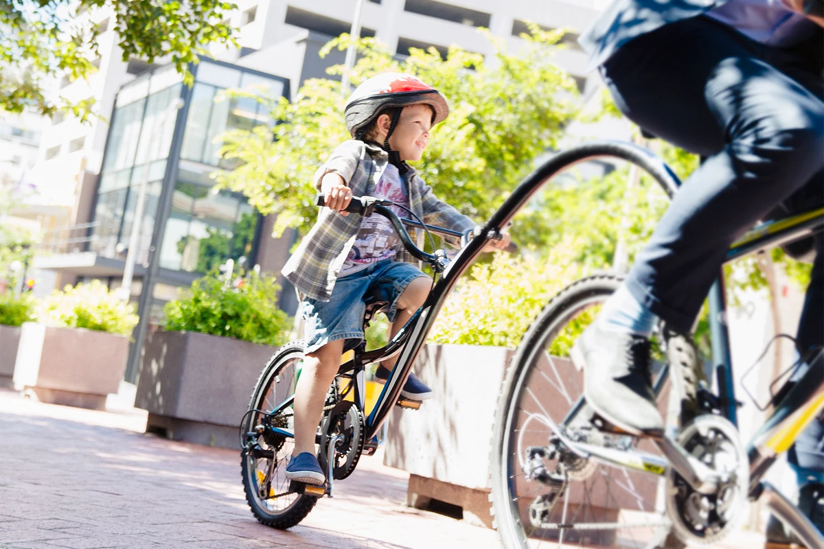 Een kind en een volwassene fietsen door een groene woonomgeving